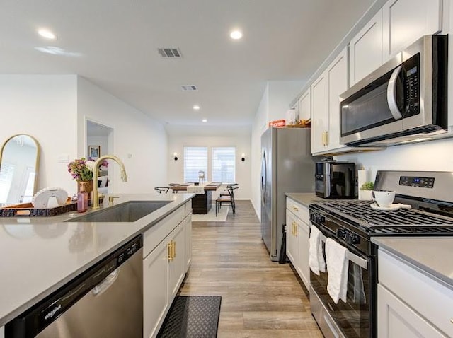 kitchen with white cabinetry, appliances with stainless steel finishes, sink, and light hardwood / wood-style floors