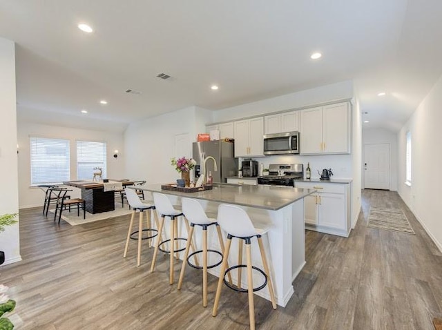 kitchen with appliances with stainless steel finishes, a kitchen island with sink, a breakfast bar area, and white cabinets