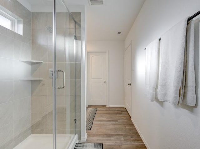 bathroom with an enclosed shower and wood-type flooring