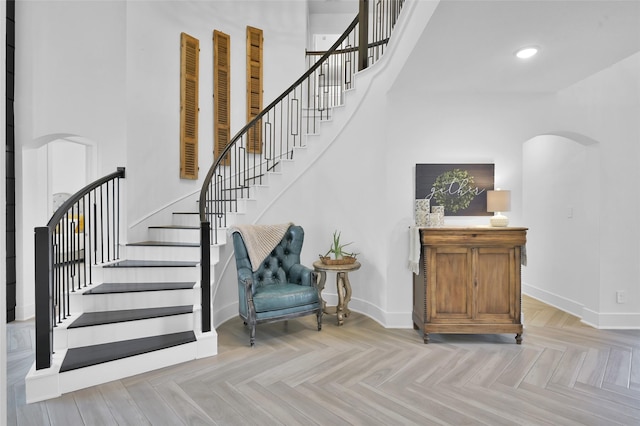 stairway with parquet flooring and a towering ceiling