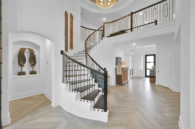 entrance foyer with an inviting chandelier, a high ceiling, and light parquet floors