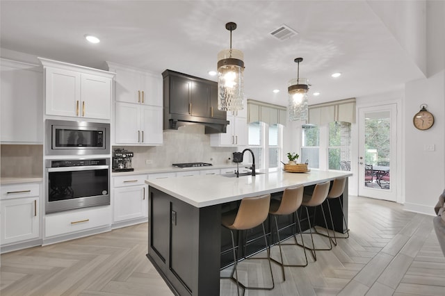 kitchen featuring a center island with sink, sink, white cabinetry, and stainless steel appliances