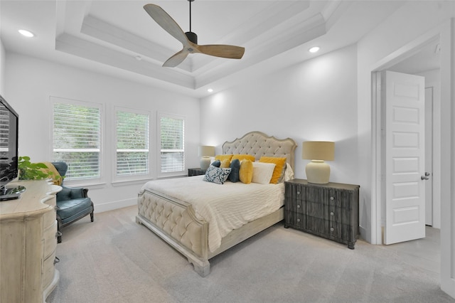 carpeted bedroom featuring a tray ceiling and ceiling fan