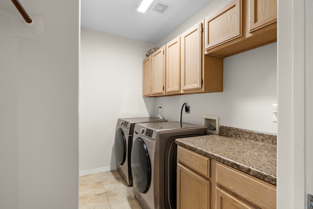 clothes washing area with light tile patterned flooring, cabinets, and washing machine and dryer