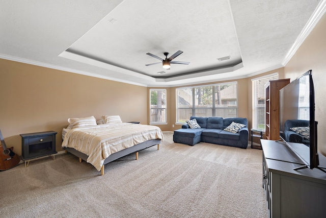 carpeted bedroom with a tray ceiling, ceiling fan, a textured ceiling, and ornamental molding