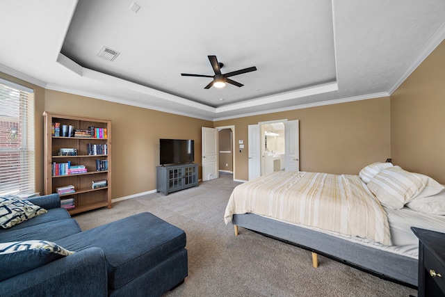 bedroom with light carpet, connected bathroom, a tray ceiling, and ceiling fan