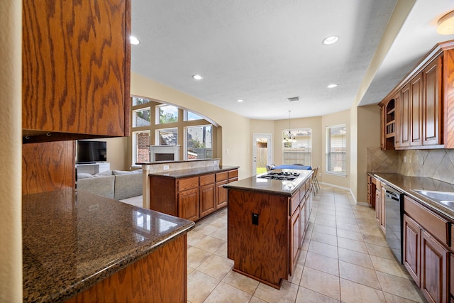 kitchen featuring decorative backsplash, dark stone counters, stainless steel appliances, light tile patterned floors, and a kitchen island