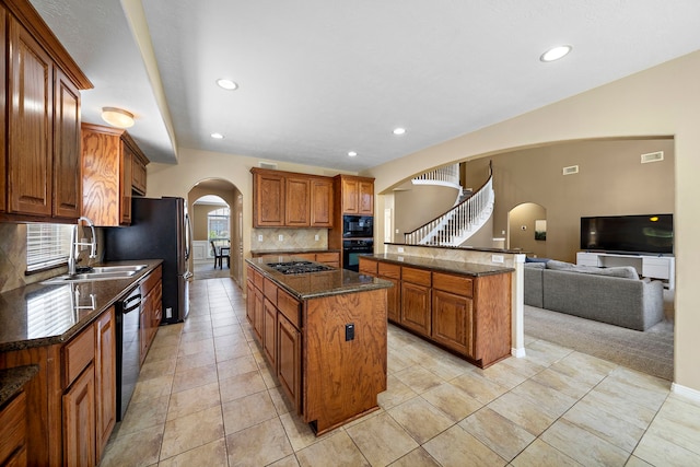 kitchen featuring a center island, sink, dark stone counters, decorative backsplash, and black appliances