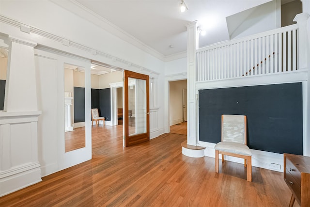 interior space with hardwood / wood-style floors, ornamental molding, a towering ceiling, and french doors