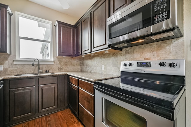 kitchen with sink, decorative backsplash, appliances with stainless steel finishes, dark brown cabinets, and dark hardwood / wood-style flooring