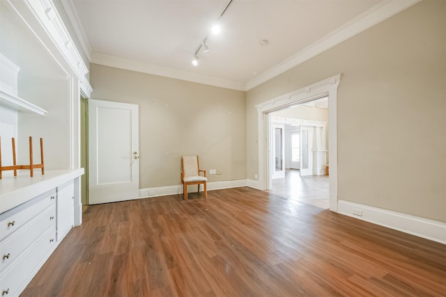 interior space with hardwood / wood-style flooring, track lighting, and ornamental molding