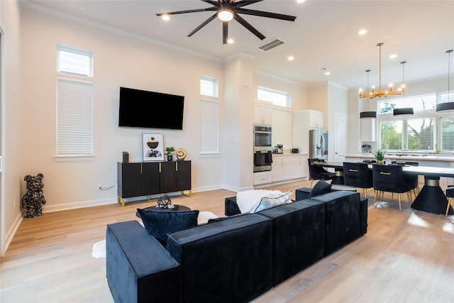 living room featuring plenty of natural light, ceiling fan with notable chandelier, and light wood-type flooring