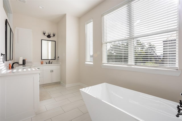 bathroom featuring a wealth of natural light, a bathtub, vanity, and tile patterned flooring