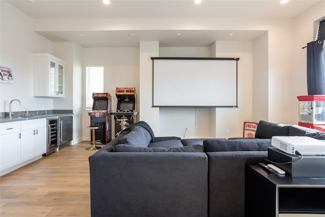 cinema with light hardwood / wood-style flooring, beverage cooler, and sink