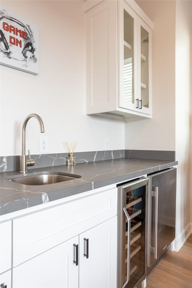 interior space with light wood-type flooring, white cabinetry, sink, and wine cooler