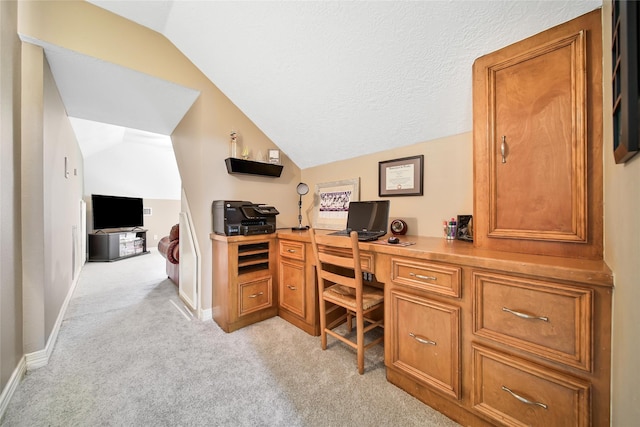 carpeted office with built in desk, a textured ceiling, and vaulted ceiling