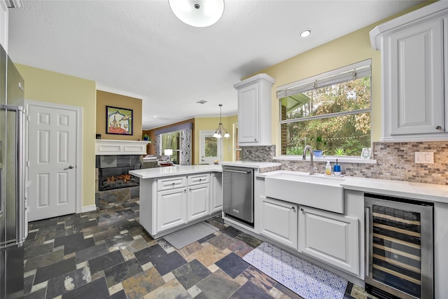 kitchen featuring kitchen peninsula, white cabinets, wine cooler, and stainless steel dishwasher