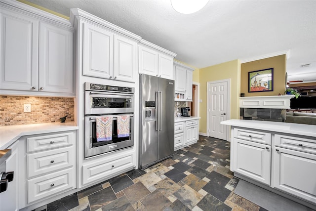 kitchen featuring appliances with stainless steel finishes, backsplash, a textured ceiling, and white cabinetry