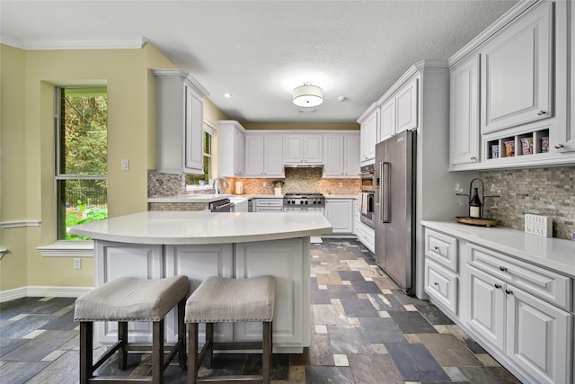 kitchen featuring a kitchen bar, white cabinetry, backsplash, and stainless steel appliances