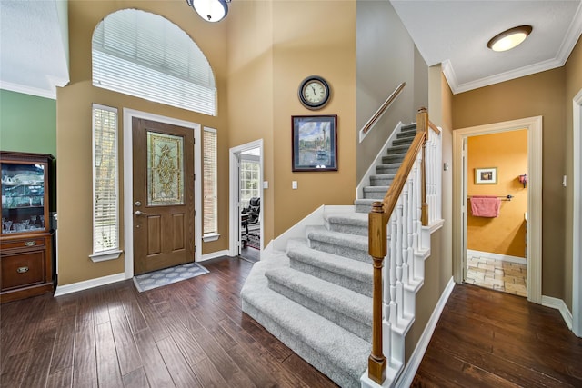 foyer entrance featuring crown molding, a towering ceiling, and dark hardwood / wood-style floors