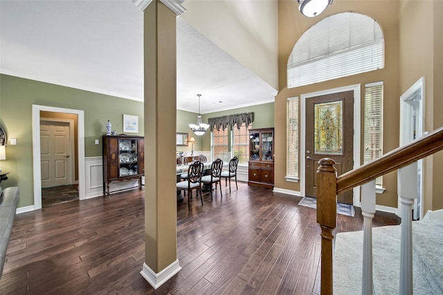 entryway with crown molding, dark wood-type flooring, a high ceiling, and an inviting chandelier