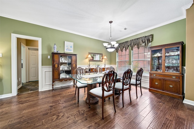 dining area featuring crown molding, dark hardwood / wood-style flooring, and an inviting chandelier