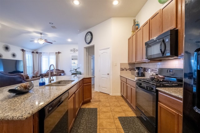 kitchen featuring light tile patterned flooring, lofted ceiling, sink, black appliances, and a center island with sink