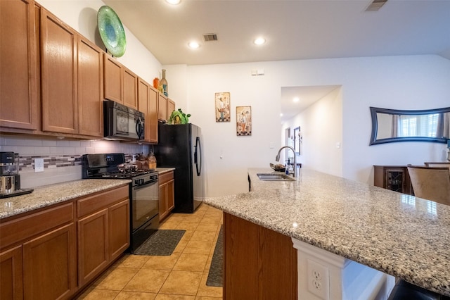 kitchen featuring sink, tasteful backsplash, light stone counters, black appliances, and light tile patterned flooring