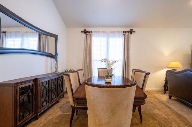 dining area featuring light tile patterned floors, vaulted ceiling, and a healthy amount of sunlight