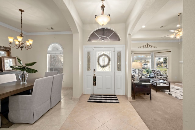 entrance foyer with light colored carpet, ceiling fan with notable chandelier, and ornamental molding