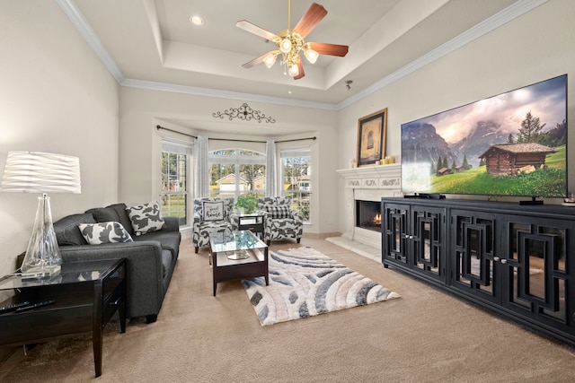 carpeted living room with a tray ceiling, ceiling fan, and crown molding