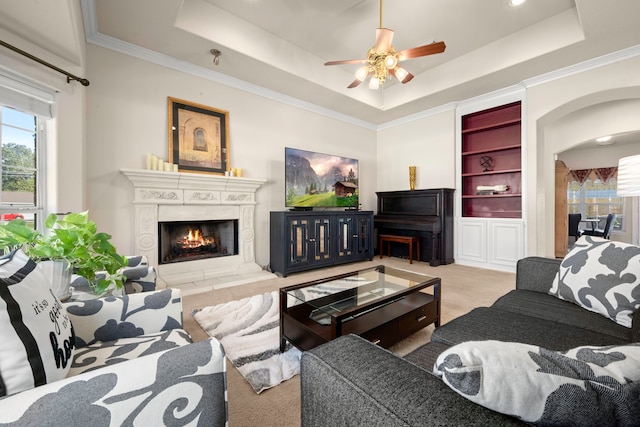 living room featuring light carpet, a tray ceiling, built in features, and ceiling fan