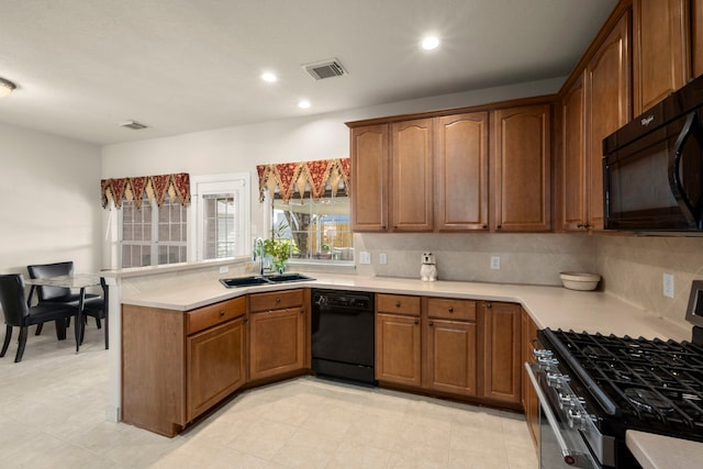 kitchen with tasteful backsplash, kitchen peninsula, sink, and black appliances