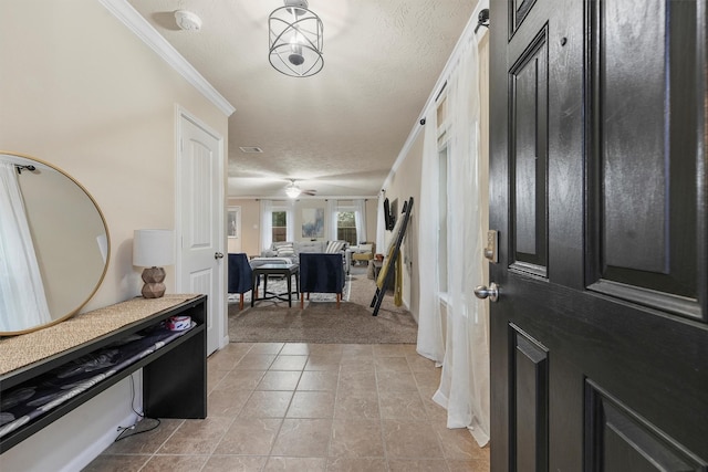 carpeted entrance foyer featuring ceiling fan, ornamental molding, and a textured ceiling