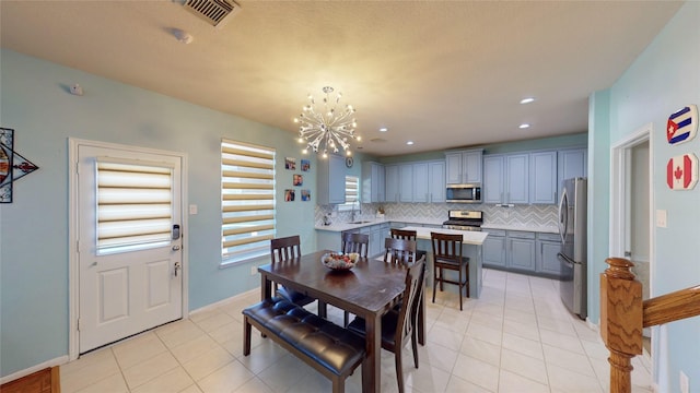 dining room with sink, light tile patterned floors, and a chandelier