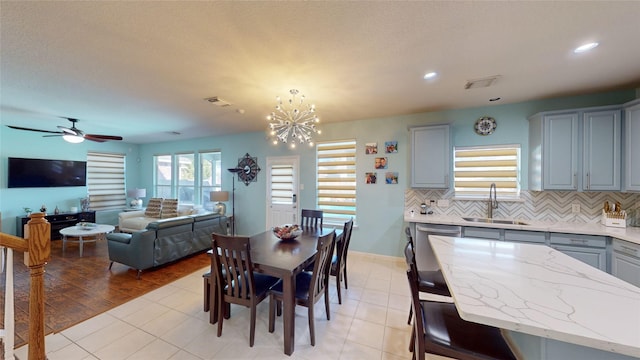 dining room with ceiling fan with notable chandelier, light hardwood / wood-style floors, and sink