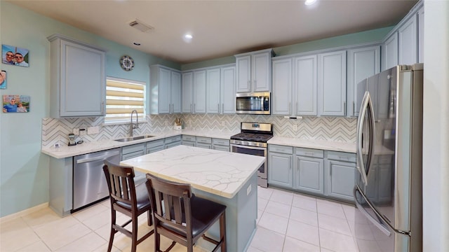 kitchen with backsplash, stainless steel appliances, a kitchen island, and sink