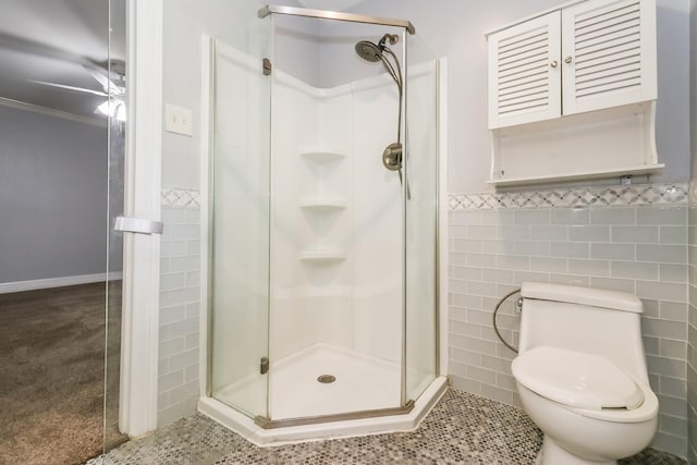 bathroom featuring ceiling fan, toilet, ornamental molding, tile walls, and walk in shower