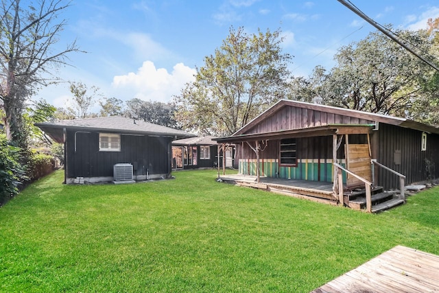 back of house featuring central air condition unit and a lawn