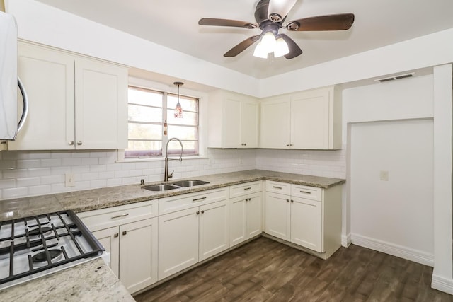 kitchen with dark wood-type flooring, sink, hanging light fixtures, light stone countertops, and tasteful backsplash