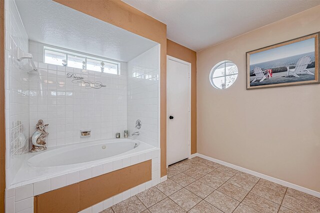 bathroom with tile patterned flooring, a textured ceiling, tiled bath, and a wealth of natural light