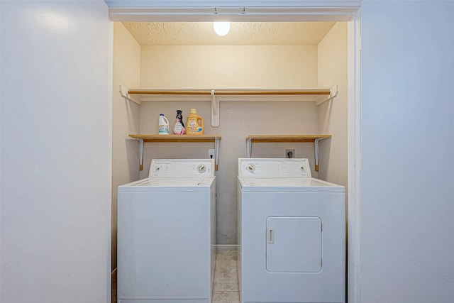 laundry area featuring washer and dryer, light tile patterned floors, and a textured ceiling