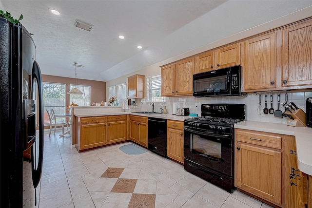 kitchen featuring decorative backsplash, kitchen peninsula, sink, black appliances, and pendant lighting