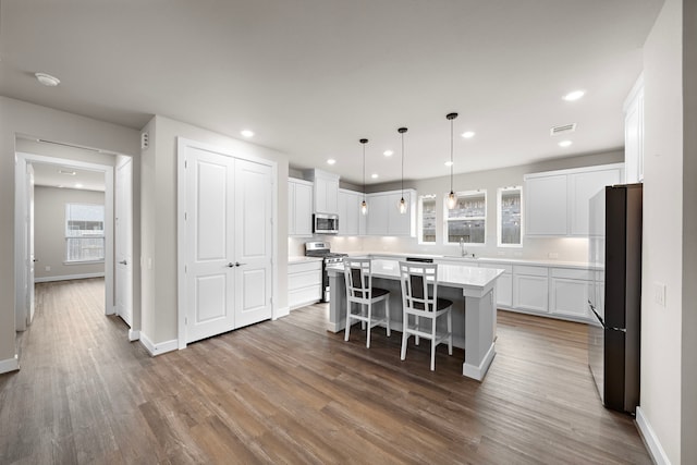 kitchen featuring white cabinets, a kitchen island, stainless steel appliances, and hardwood / wood-style flooring