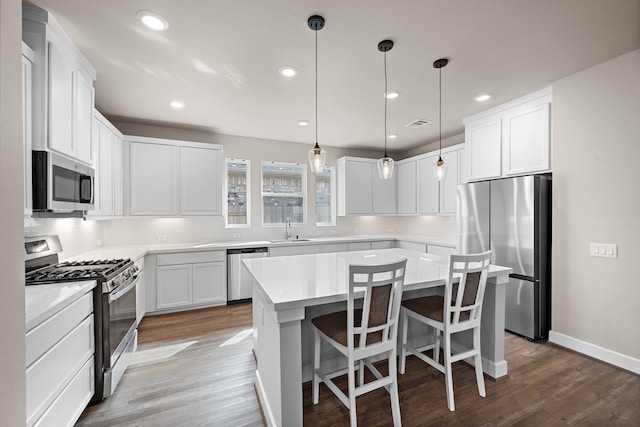 kitchen with sink, dark wood-type flooring, a kitchen island, white cabinets, and appliances with stainless steel finishes