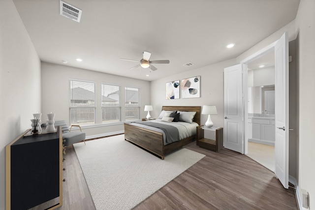 bedroom with hardwood / wood-style floors, ensuite bathroom, ceiling fan, and sink