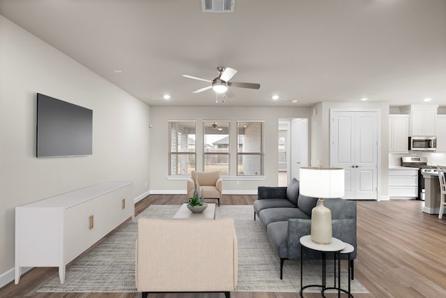 living room with light wood-type flooring and ceiling fan