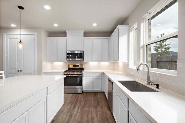 kitchen with hanging light fixtures, sink, white cabinets, and stainless steel appliances