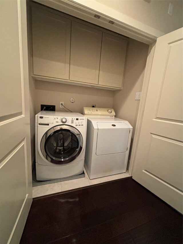 clothes washing area with cabinets, hardwood / wood-style floors, and separate washer and dryer