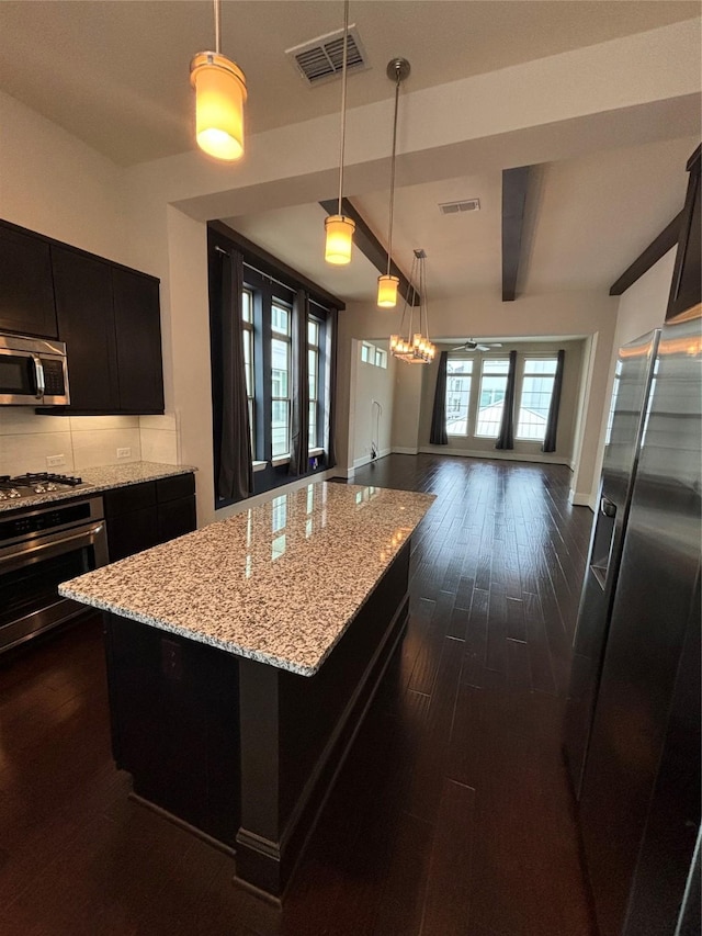 kitchen featuring appliances with stainless steel finishes, ceiling fan, dark wood-type flooring, beam ceiling, and a center island